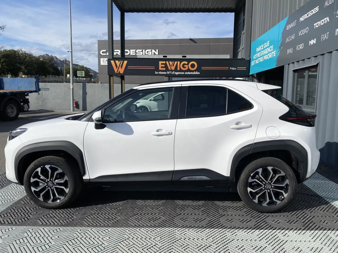 Profil côté gauche de la Toyota Yaris Cross blanche pure 2025 avec jantes alliage et toit noir contrasté.