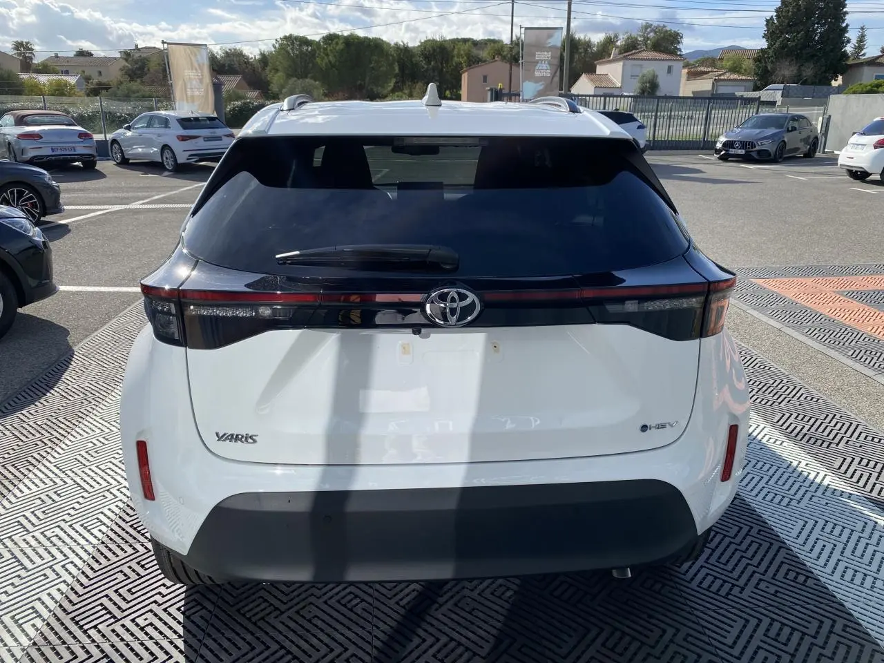 Vue arrière d'une Toyota Yaris Cross blanche avec lunette arrière noire et feux arrière LED horizontaux.