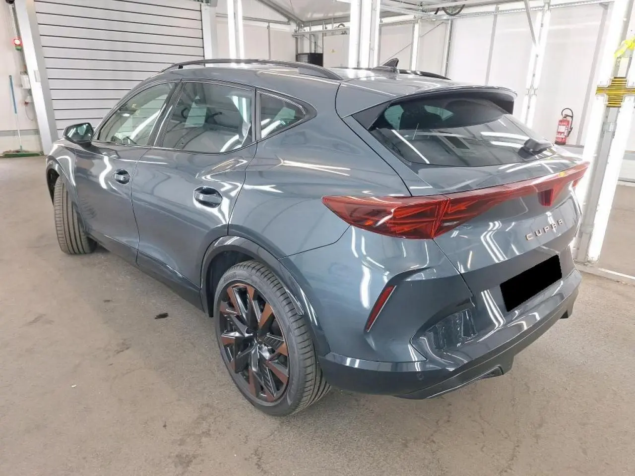 Vue 3/4 arrière droite d'une CUPRA Formentor gris magnétique avec jantes cuivrées et feux arrière en bandeau lumineux