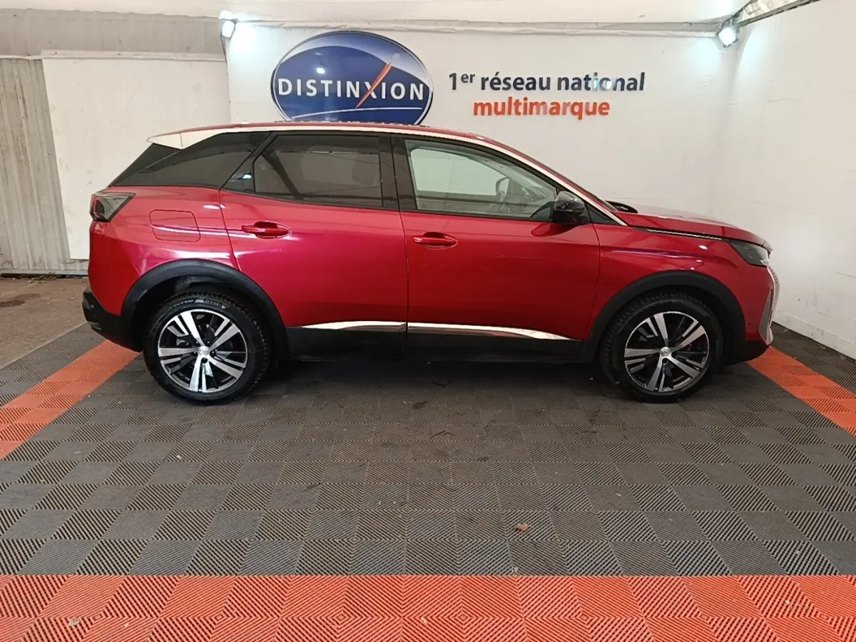 Vue de profil côté droit d’un Peugeot 3008 PureTech 130 rouge avec jantes alliage et toit noir dans un showroom.
