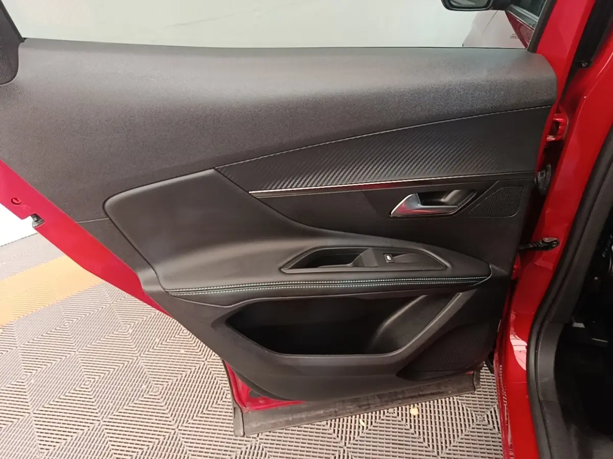 Vue intérieure de la porte avant gauche rouge du Peugeot 3008 PureTech 130 S&S Allure avec garniture noire et surpiqûres bleues.