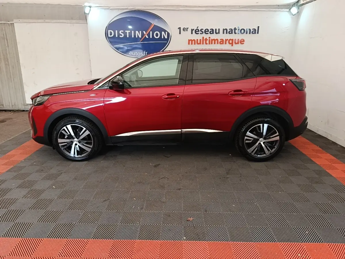 Vue latérale droite d'un Peugeot 3008 PureTech 130 rouge avec toit noir et jantes alliage bicolores en showroom.