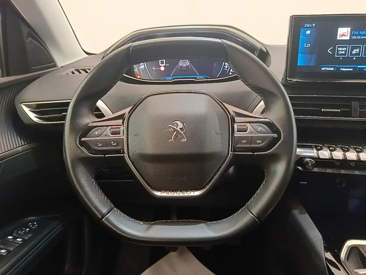 Vue intérieure centrée sur le volant cuir noir du Peugeot 3008 avec tableau de bord numérique et écran tactile.