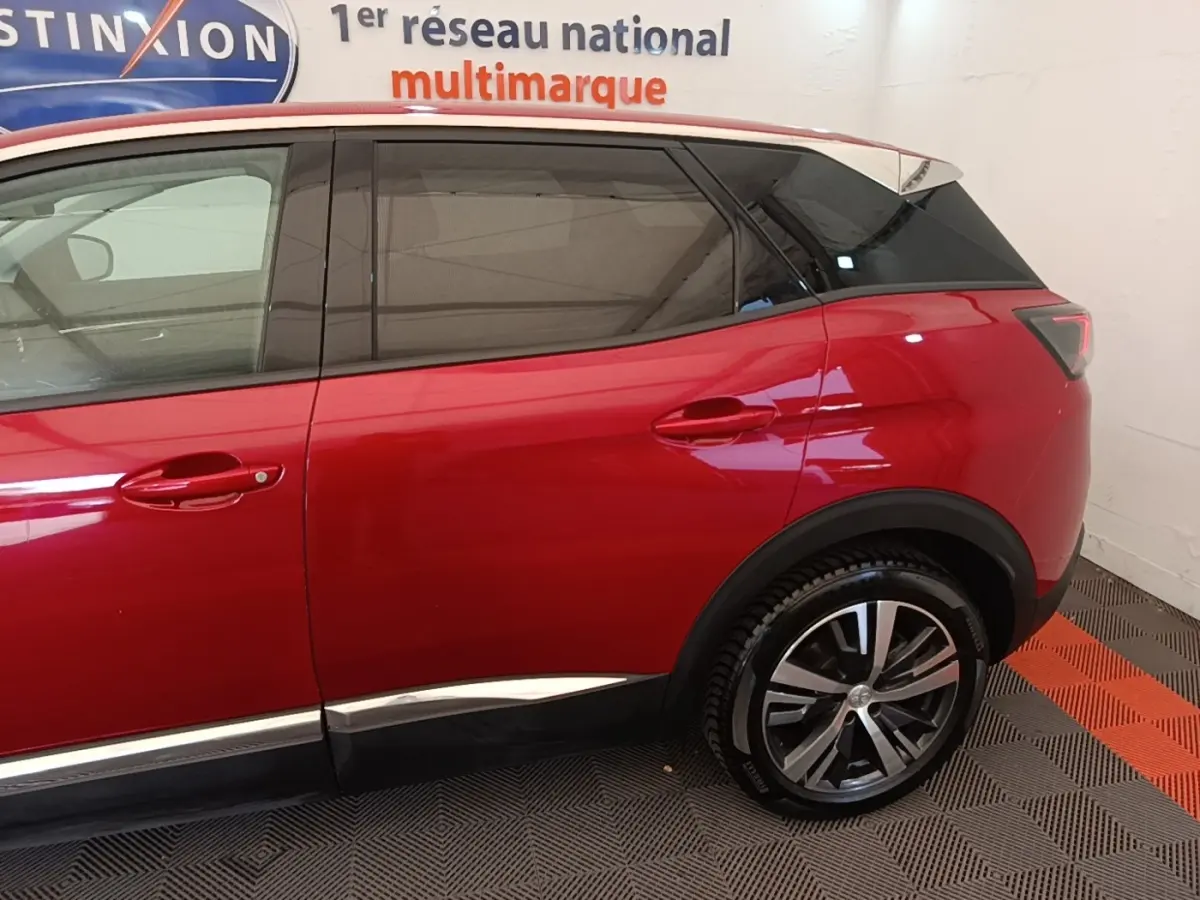 Vue latérale droite d’un Peugeot 3008 rouge avec jantes alliage et vitres teintées, intérieur showroom.