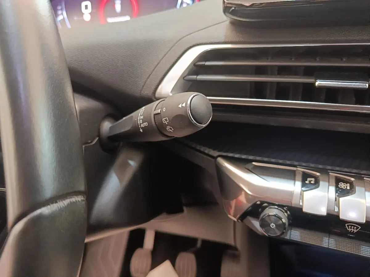 Gros plan intérieur sur la commande d’essuie-glace et la console centrale noire du Peugeot 3008 PureTech 130 S&S Allure 2021.