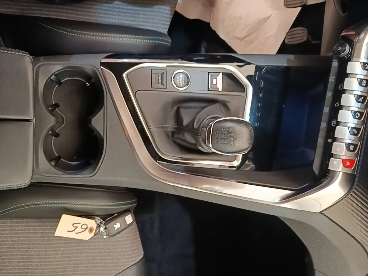 Vue rapprochée de la console centrale noire du Peugeot 3008 PureTech 130 avec levier de vitesse manuel et porte-gobelets.