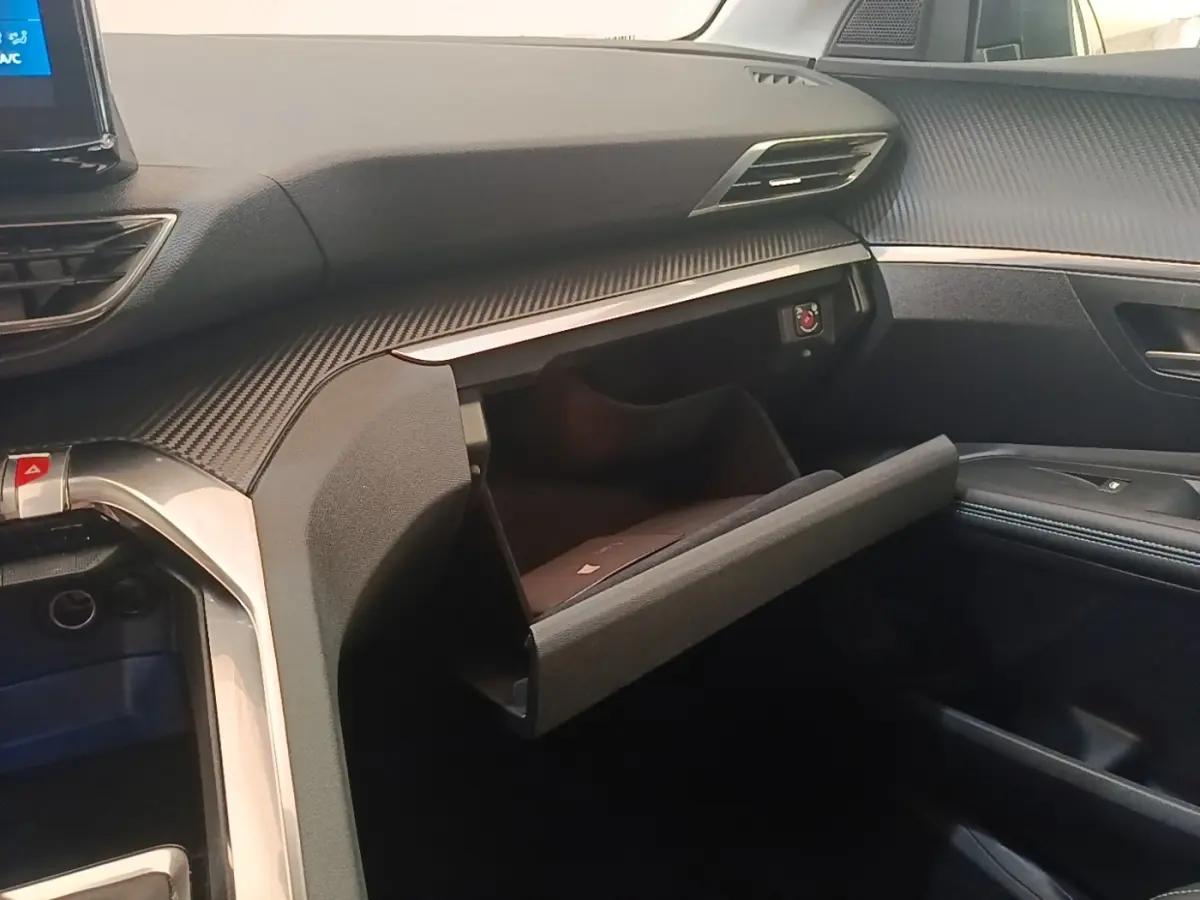 Intérieur du Peugeot 3008 PureTech 130 S&S Allure 2021, vue côté passager avec boîte à gants ouverte et tableau de bord noir.