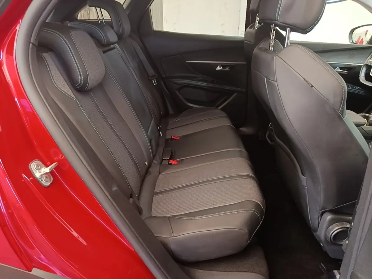 Vue intérieure côté gauche sur la banquette arrière grise du Peugeot 3008 PureTech 130 S&S Allure rouge, avec sièges en tissu et cuir.