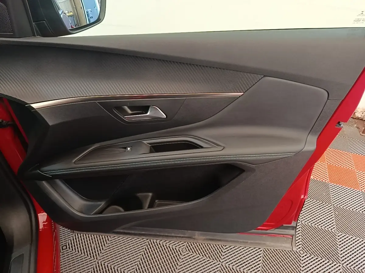Vue latérale du panneau de porte avant gauche rouge du Peugeot 3008 avec garniture noire et insert décoratif chrome.