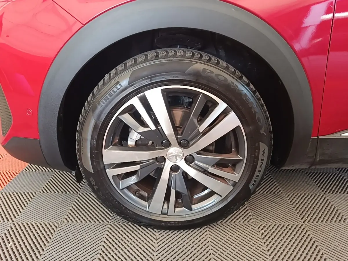 Gros plan sur la roue avant gauche du Peugeot 3008 rouge, jante alliage bicolore et pneu hiver Pirelli.