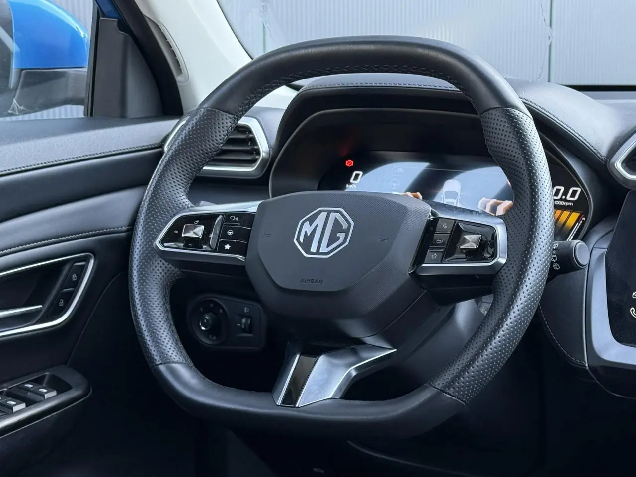 Vue rapprochée du volant en cuir noir perforé du MG ZS 1.5 Hybrid+ 197 Luxury avec tableau de bord numérique.