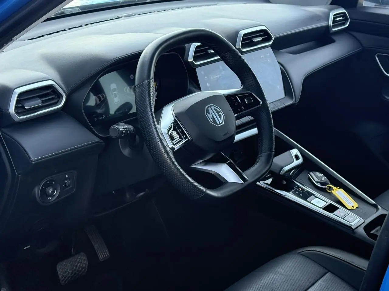 Vue intérieure côté conducteur du MG ZS 1.5 Hybrid+ 197 Luxury, volant cuir noir et écran tactile central.