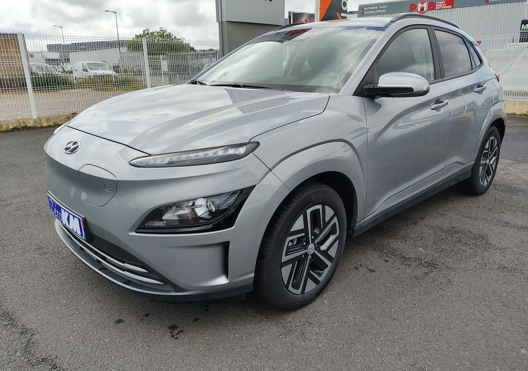 Vue 3/4 avant droit d'un Hyundai Kona électrique gris métallisé avec jantes alliage et calandre fermée.