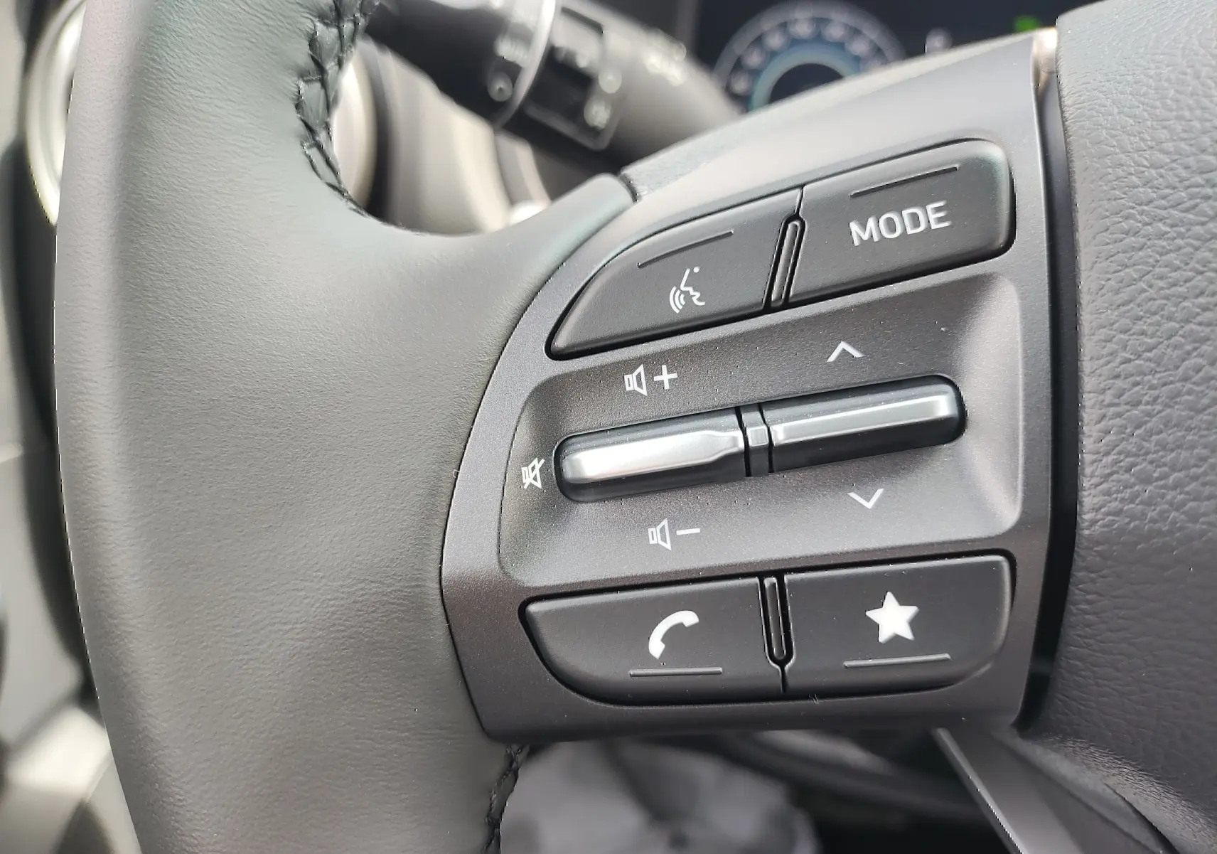 Gros plan sur les commandes audio et téléphone au volant cuir noir du Hyundai Kona Electric 2025.