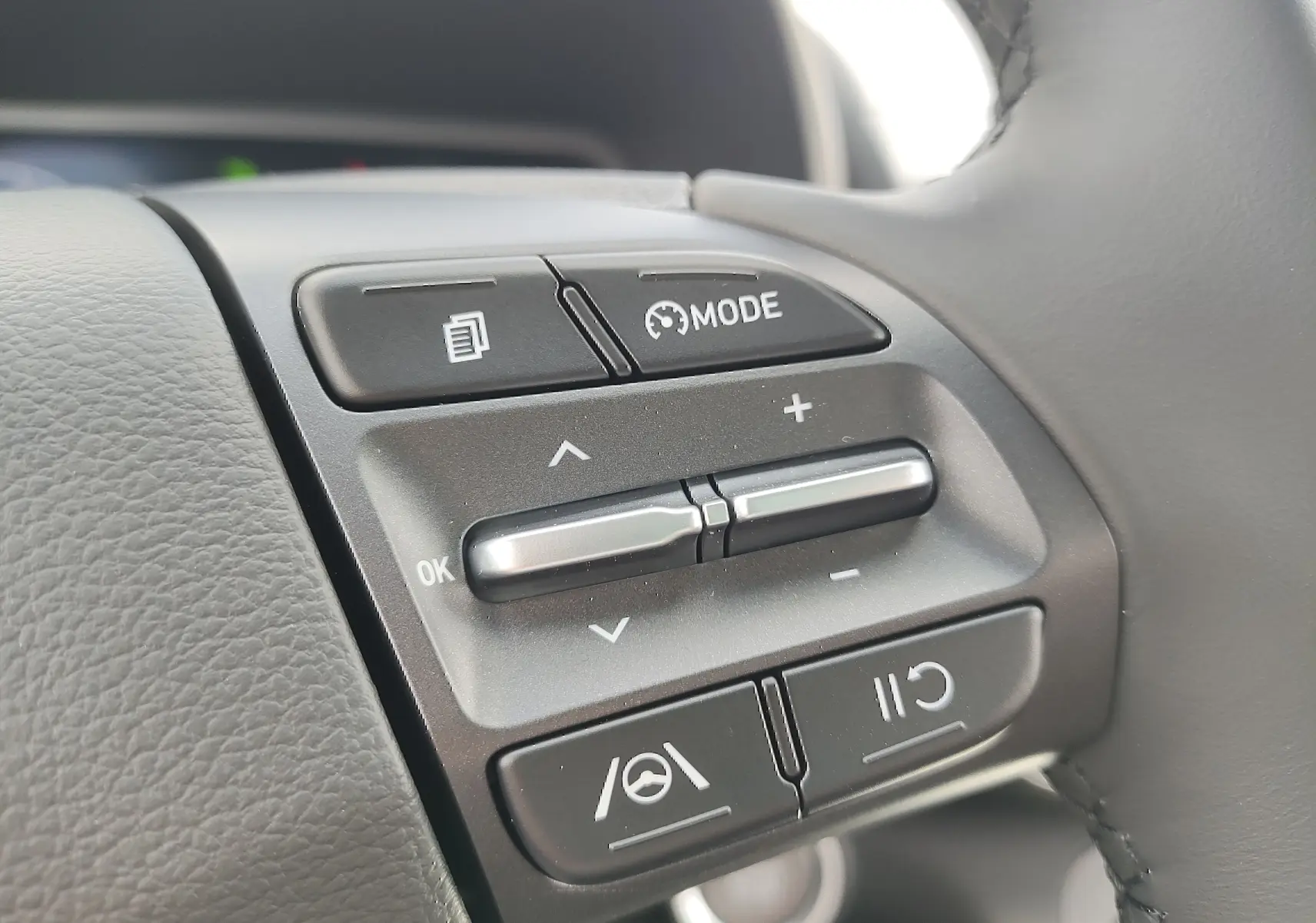 Gros plan sur les commandes multifonctions au volant cuir du Hyundai Kona Electric gris métallisé 2025.