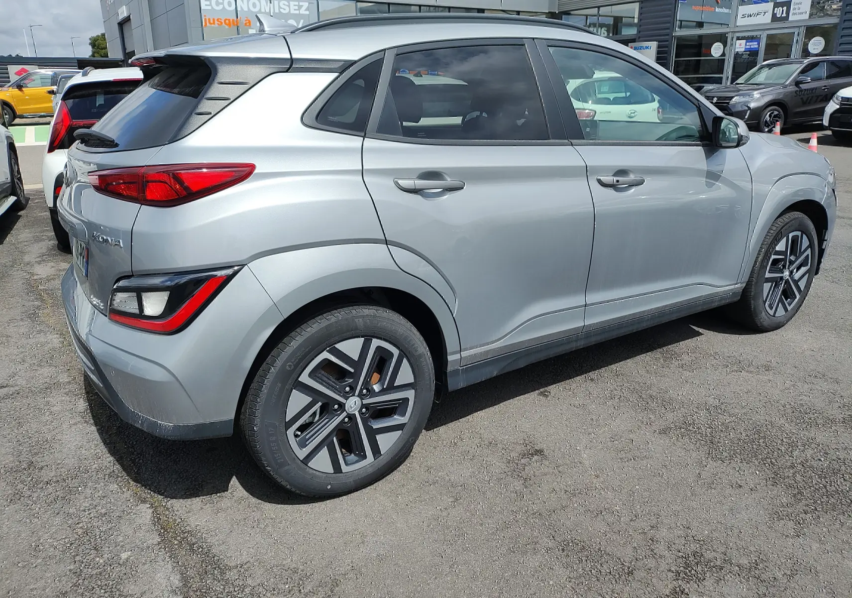 Vue 3/4 arrière côté gauche d'un Hyundai Kona électrique gris métallisé avec jantes alliage et vitres surteintées.