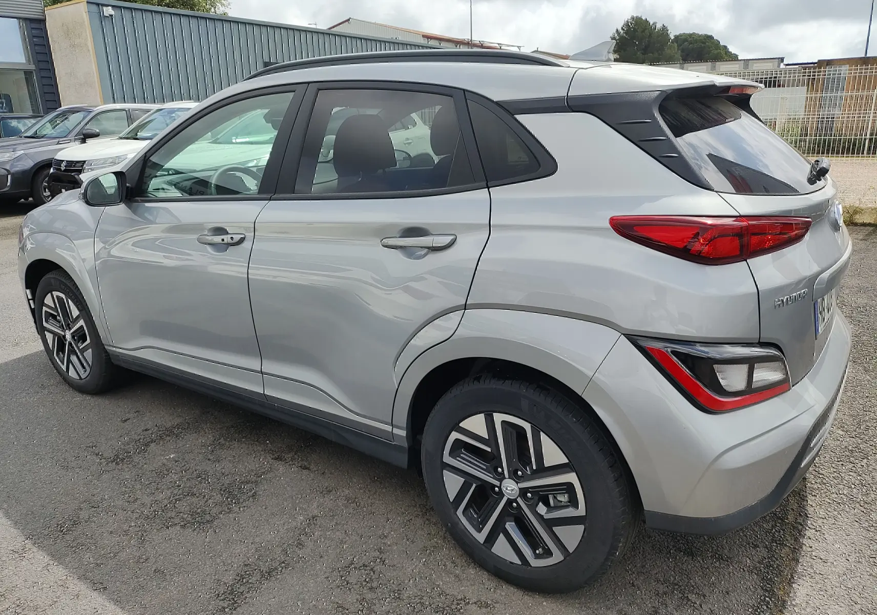 Vue 3/4 arrière côté gauche d'un Hyundai Kona électrique gris métallisé avec jantes alliage et vitres surteintées.