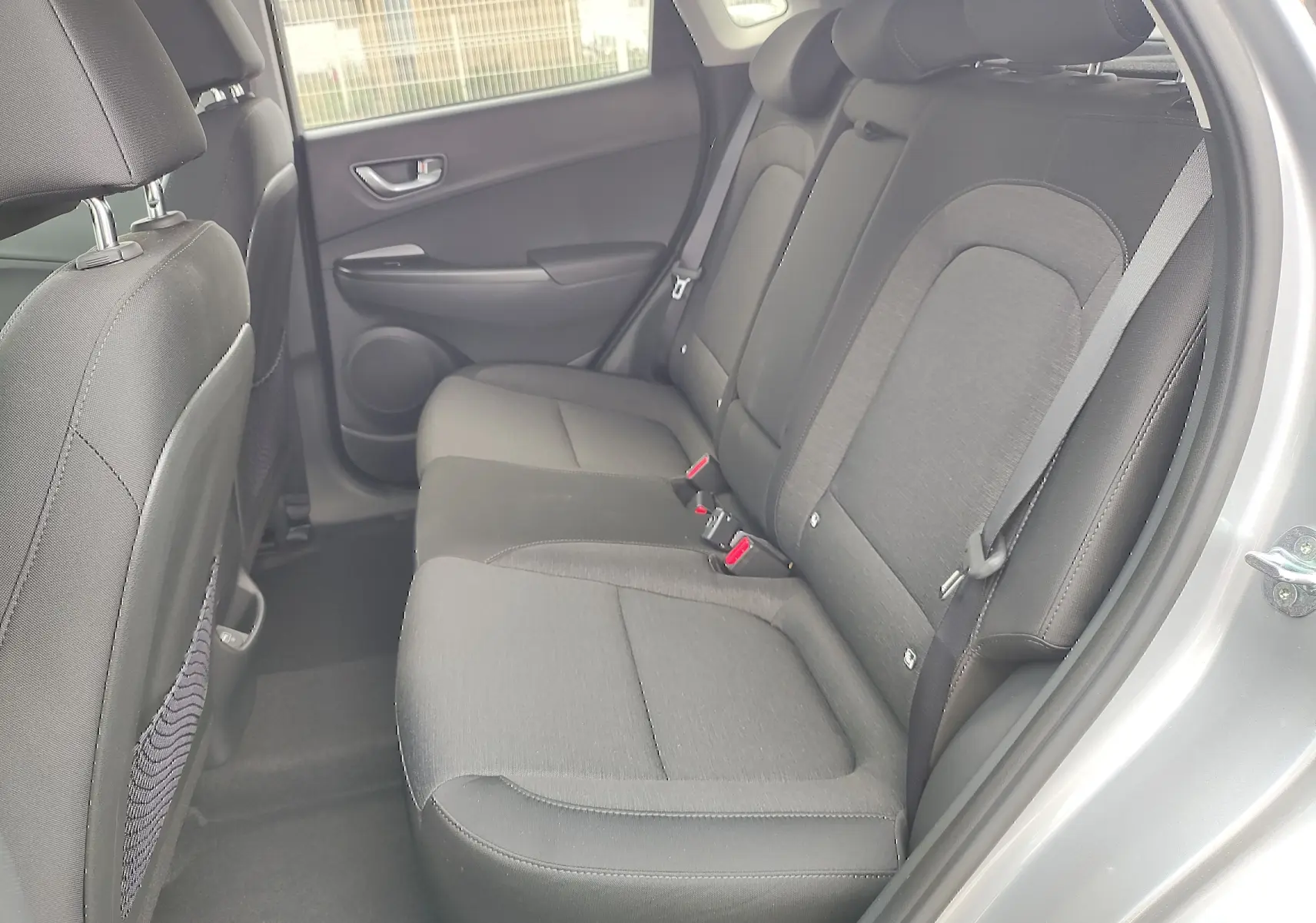 Vue côté droit de la banquette arrière noire du Hyundai Kona Electric gris métallisé avec ceintures de sécurité visibles.