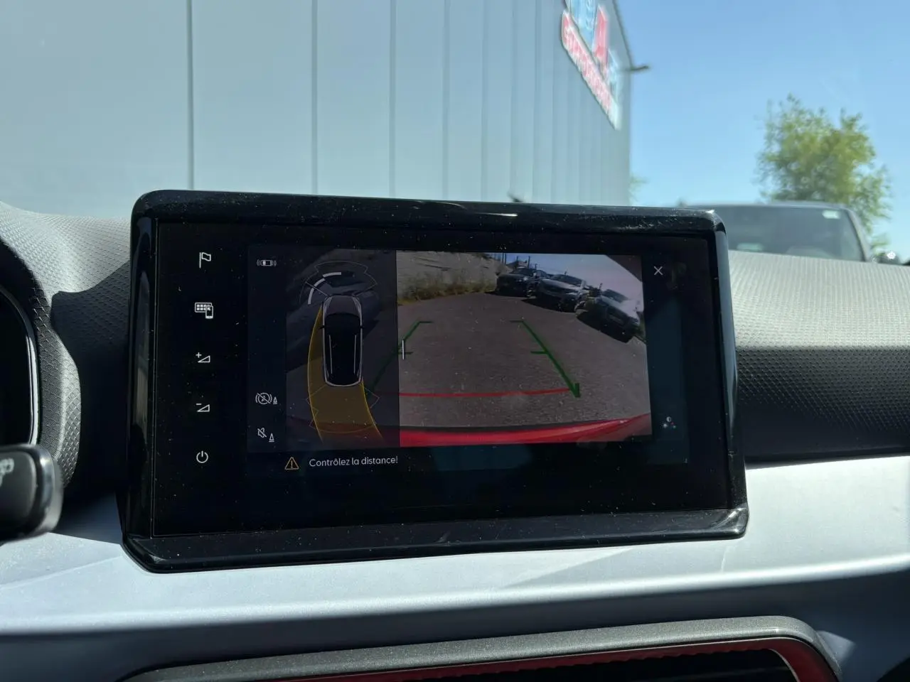 Écran tactile intérieur montrant la caméra de recul du SEAT Arona Rouge Désir avec lignes de guidage vertes et rouges.