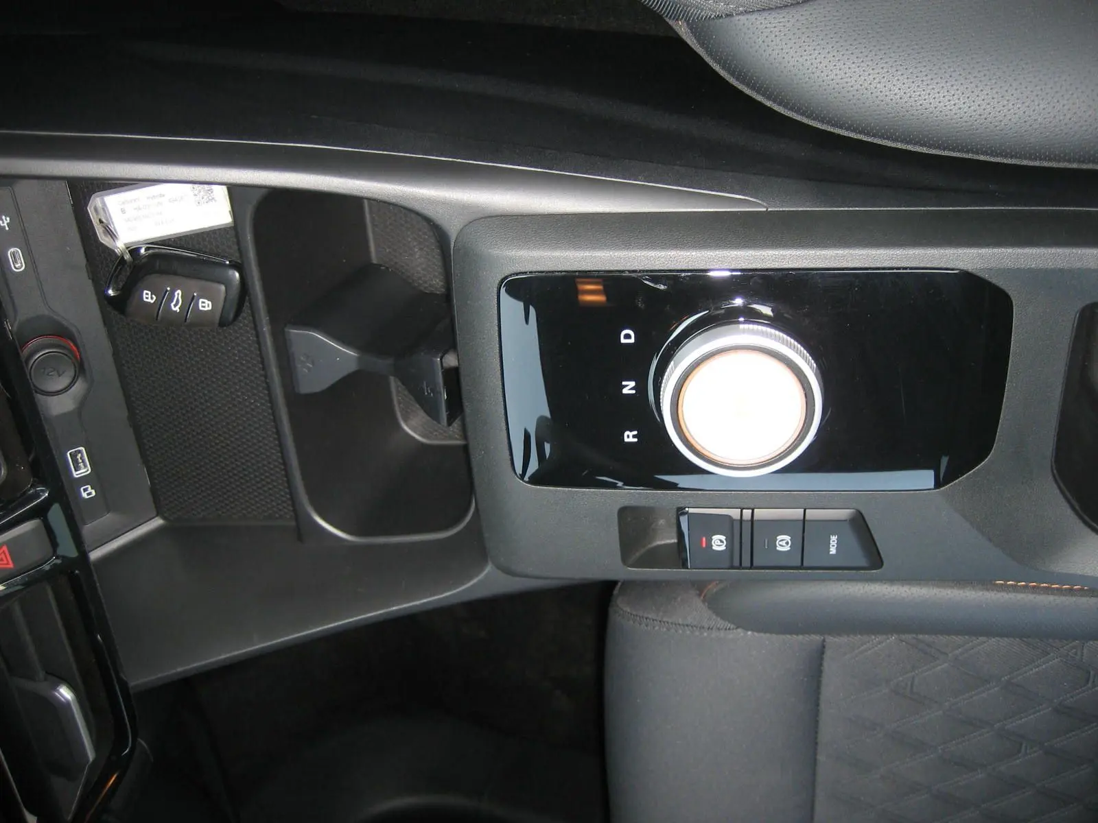 Vue rapprochée de la console centrale noire du MG3 1.5 HYBRID+ 2024, mettant en valeur la molette de boîte automatique et les boutons de frein à main.