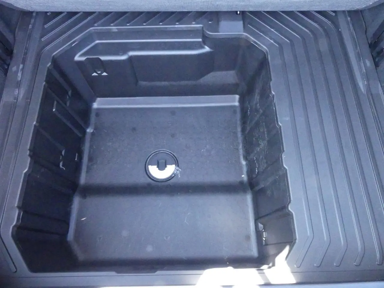Compartiment de rangement sous plancher de coffre du Ford Puma 2025, vue plongeante sur espace de stockage noir.