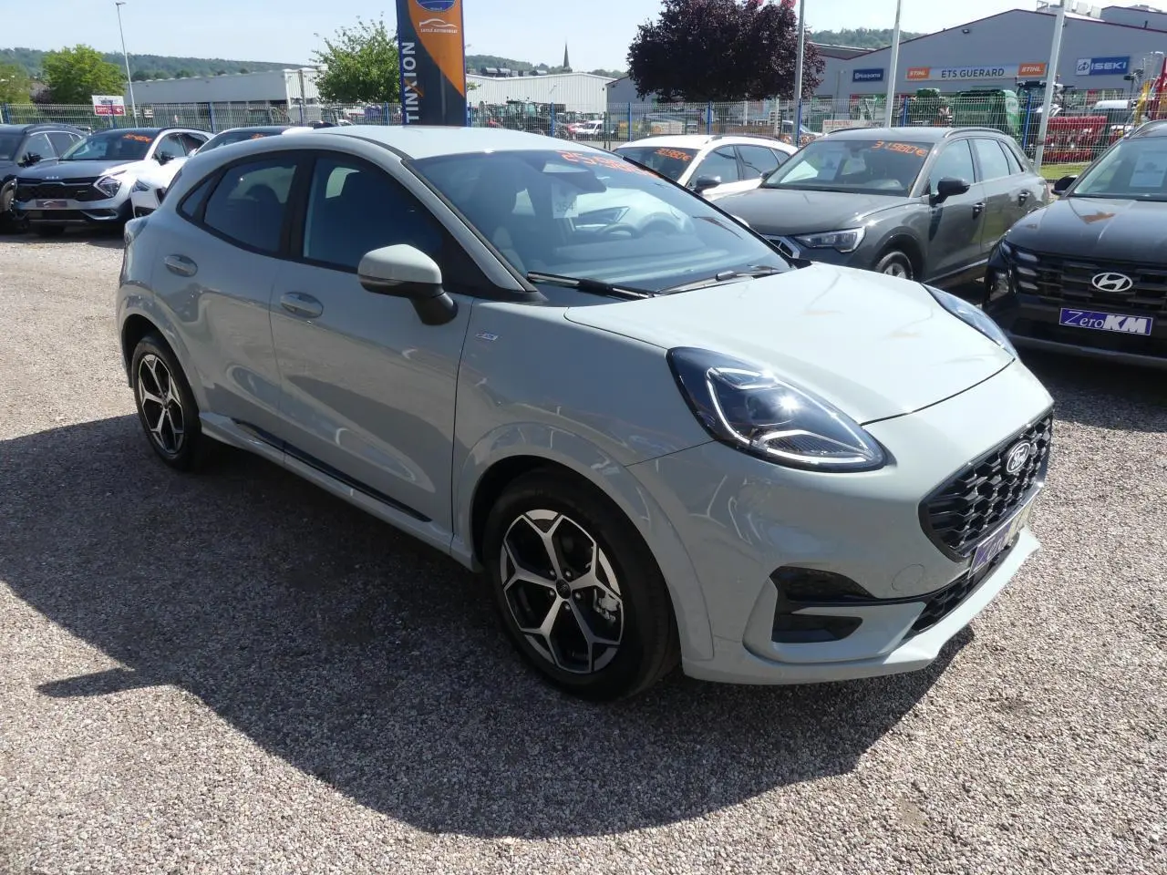 Ford Puma 2025 gris métallisé en vue 3/4 avant droit, avec jantes alliage et calandre noire sportive.