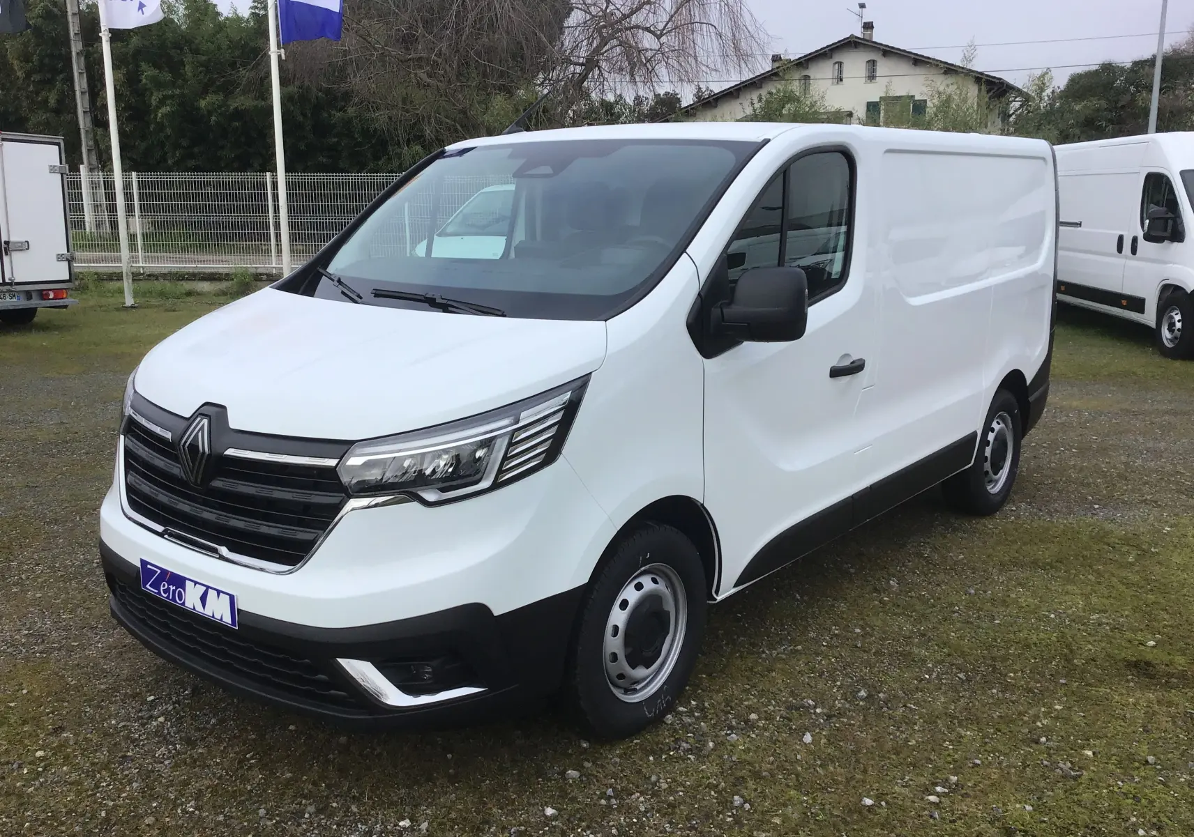 Renault Trafic Fourgon blanc vu en 3/4 avant droit, avec calandre noire et feux LED distinctifs.