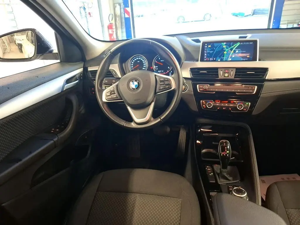 Vue intérieure avant du BMW X2 avec tableau de bord noir, volant multifonction et écran de navigation central.