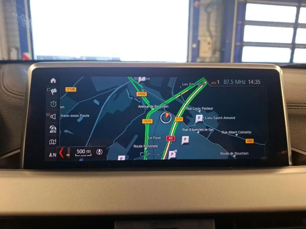 Écran central du GPS de BMW X2 blanc, affichant une carte routière avec itinéraire et trafic en temps réel.