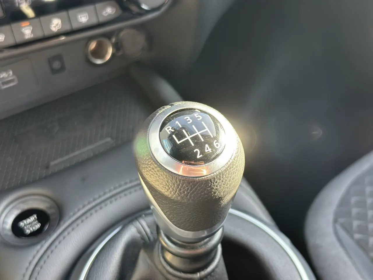 Gros plan sur le levier de vitesses manuel noir du Nissan Juke 2025 avec bouton démarrage visible en arrière-plan.