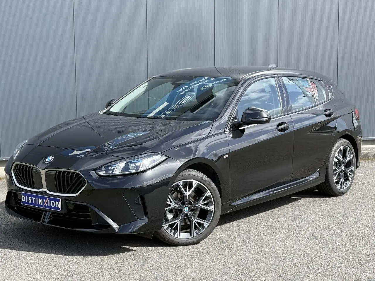BMW Série 1 118d M Sport Saphirschwarz vue 3/4 avant droit avec jantes alliage 18 pouces et calandre noire.
