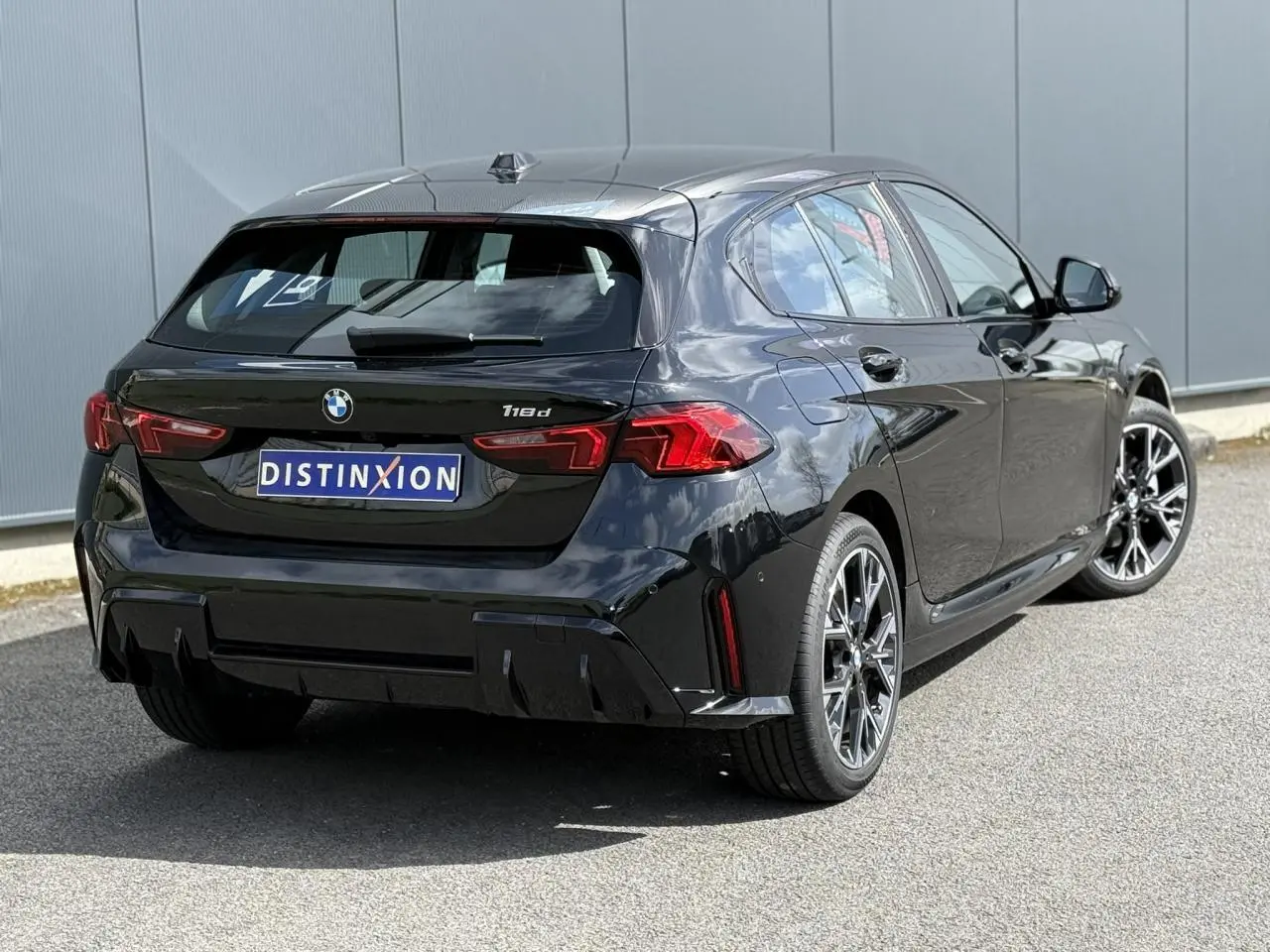 Vue 3/4 arrière droite d'une BMW Série 1 118d M Sport Saphirschwarz avec jantes alliage 18 pouces et feux LED.