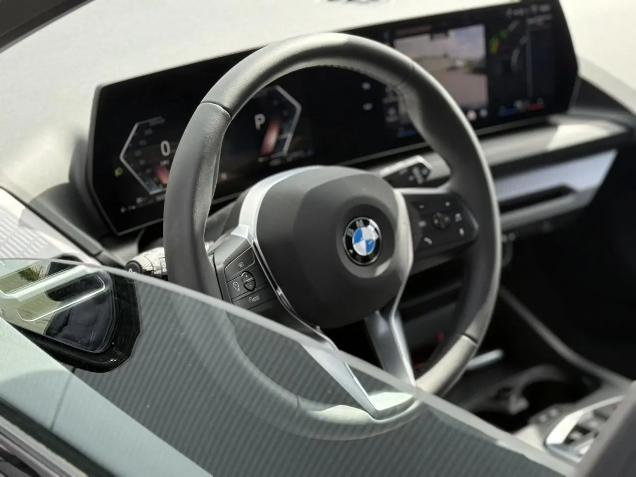 Vue rapprochée du volant multifonctions noir et du tableau de bord numérique de la BMW Série 1 118dA 2025.