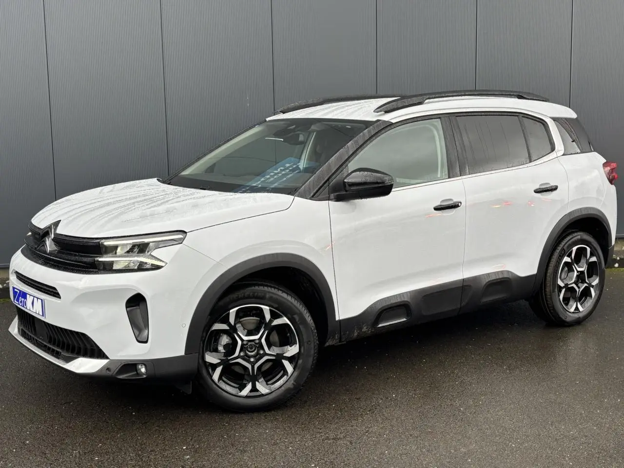 SUV Citroën C5 Aircross blanc Okénite en 3/4 avant droit avec jantes alliage bi-ton et barres de toit noires.