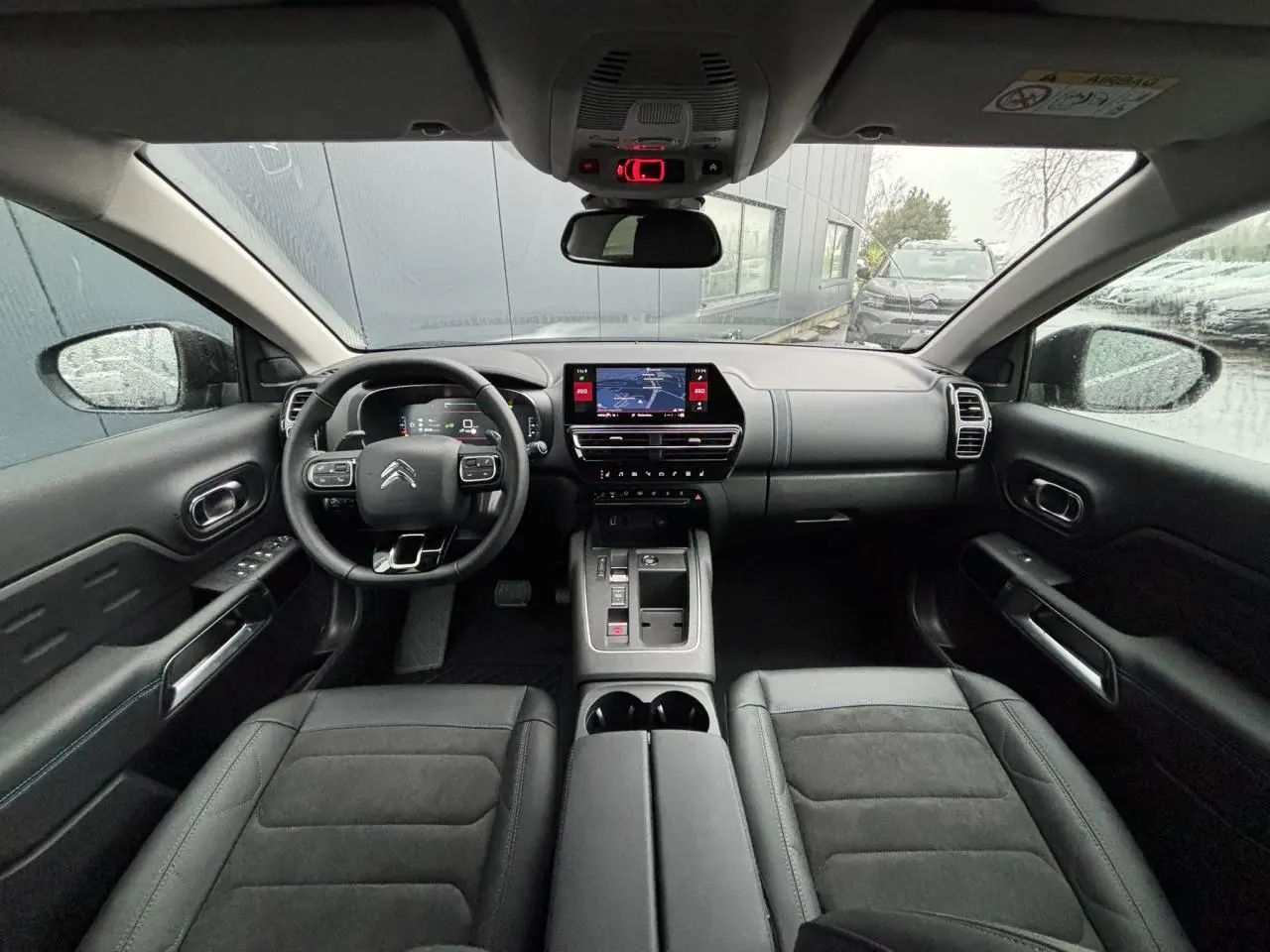 Vue intérieure avant du Citroën C5 Aircross 2025 avec tableau de bord noir, écran tactile et sièges en Alcantara noir.