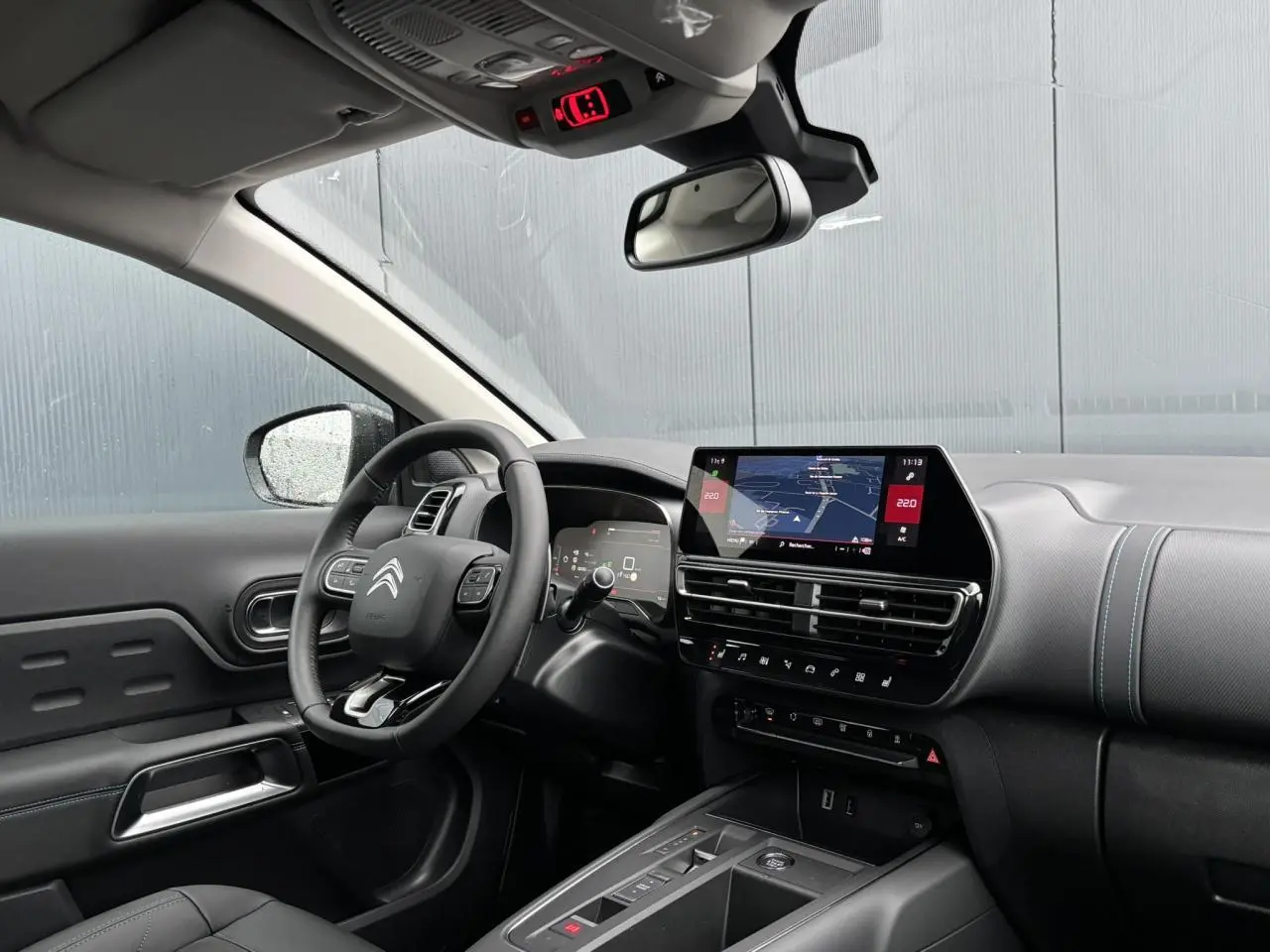 Vue intérieure côté conducteur du Citroën C5 Aircross 2025, tableau de bord noir avec écran tactile et volant multifonction.