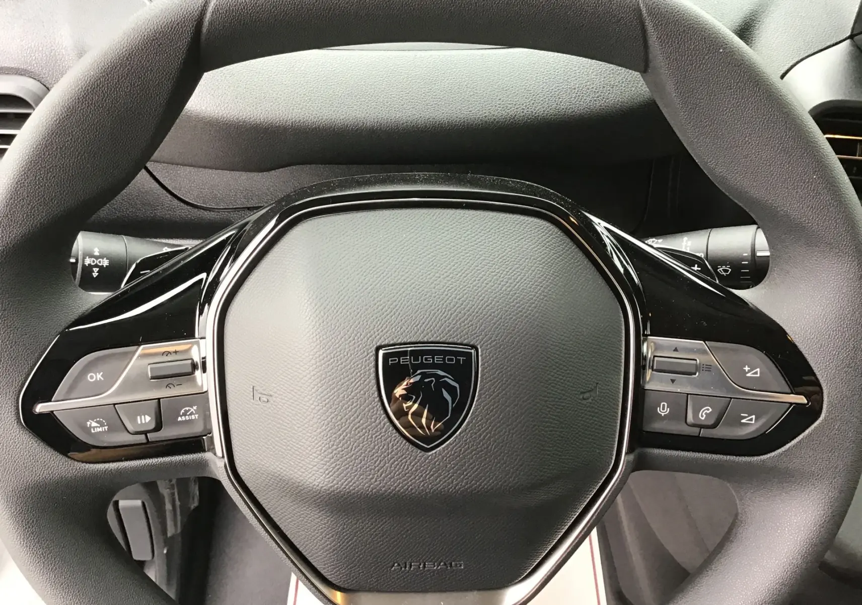 Gros plan sur le volant noir du Peugeot Partner blanc 2026 avec commandes intégrées et logo lion central.