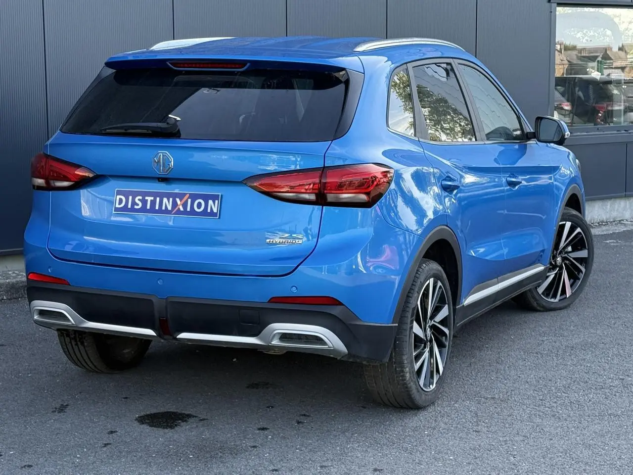Vue 3/4 arrière droite du MG ZS 1.5 Hybrid+ 197 Luxury bleu Como avec jantes alliage et vitres surteintées.