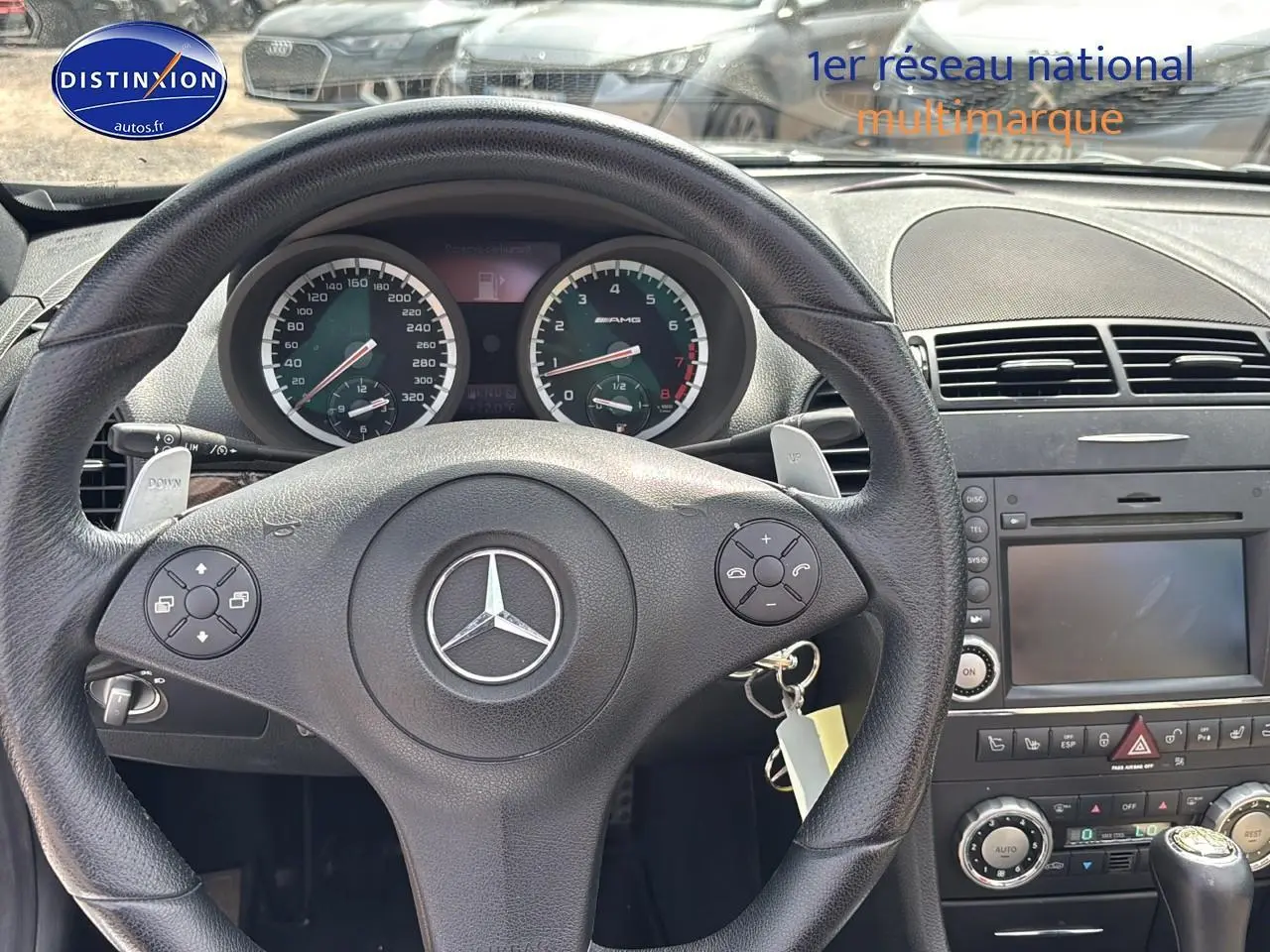 Vue intérieure centrée sur le volant cuir noir et le tableau de bord du Mercedes SLK 55 AMG 2009 avec commandes intégrées.