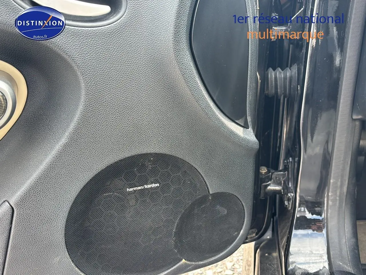 Gros plan sur la porte avant gauche noire d'une Mercedes SLK 55 AMG 7G-Tronic avec haut-parleur Harman Kardon intégré.
