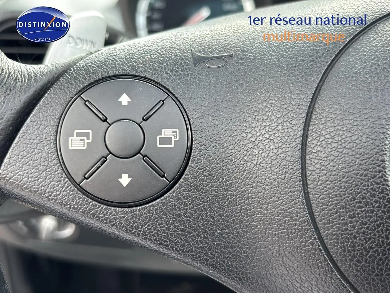 Gros plan sur le volant en cuir noir du Mercedes SLK 55 AMG 7G-Tronic de 2009, montrant les commandes intégrées.