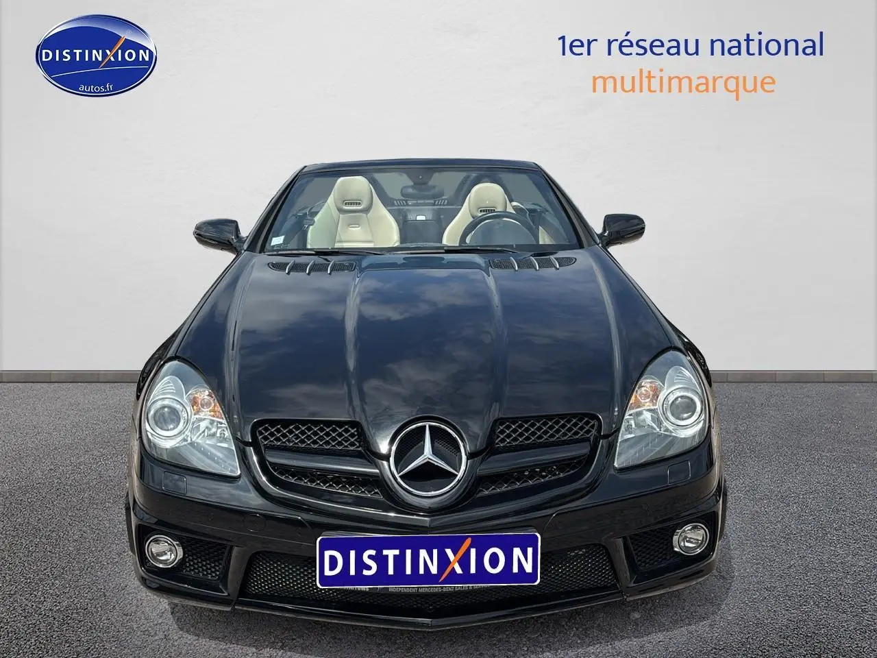 Vue frontale d'une Mercedes SLK 55 AMG noire de 2009, découvrable avec sièges cuir clairs visibles.