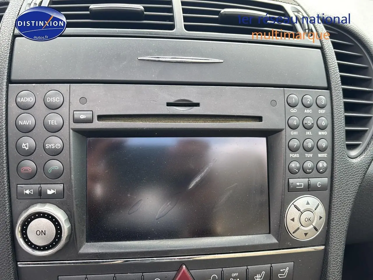 Tableau de bord noir de la Mercedes SLK 55 AMG 7G-Tronic 2009, avec écran central et commandes audio intégrées.