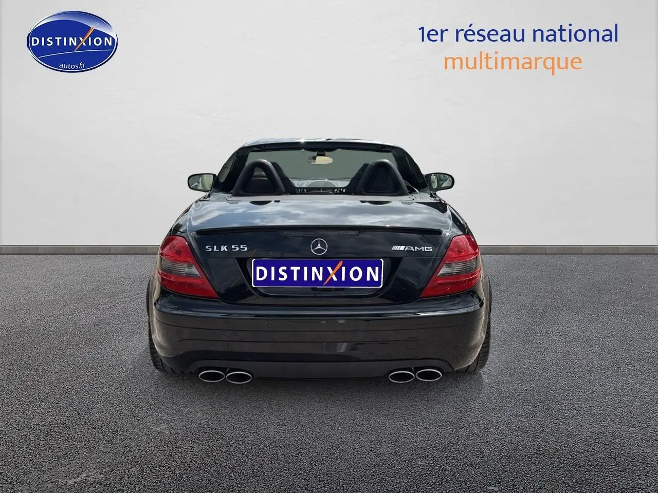 Vue arrière d'une Mercedes SLK 55 AMG noire de 2009, avec double sortie d'échappement et capote ouverte.