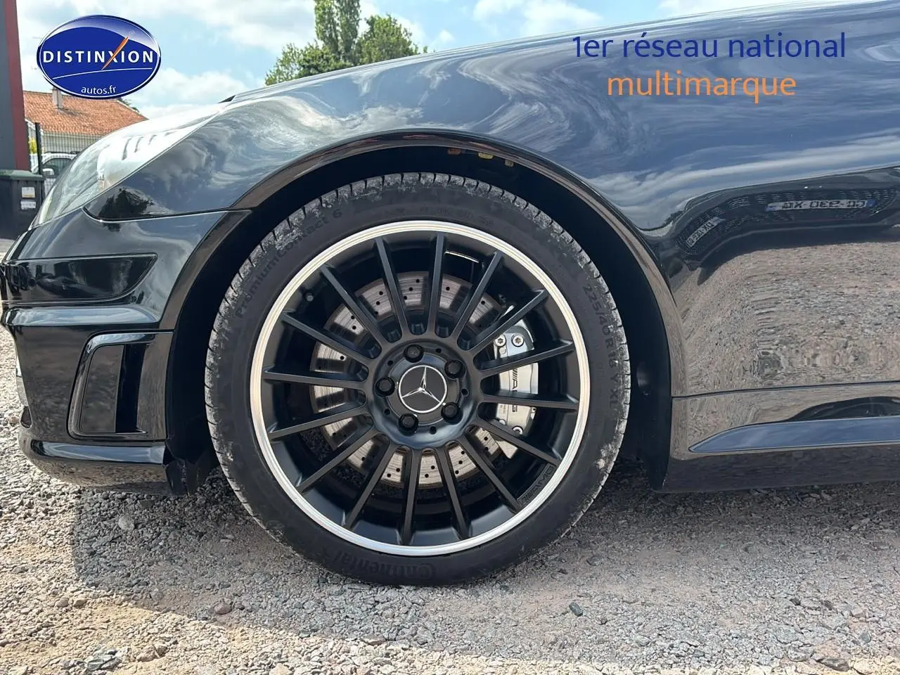 Gros plan sur la roue avant gauche noire d'une Mercedes SLK 55 AMG 7G-Tronic avec jante alu noire et logo Mercedes central.