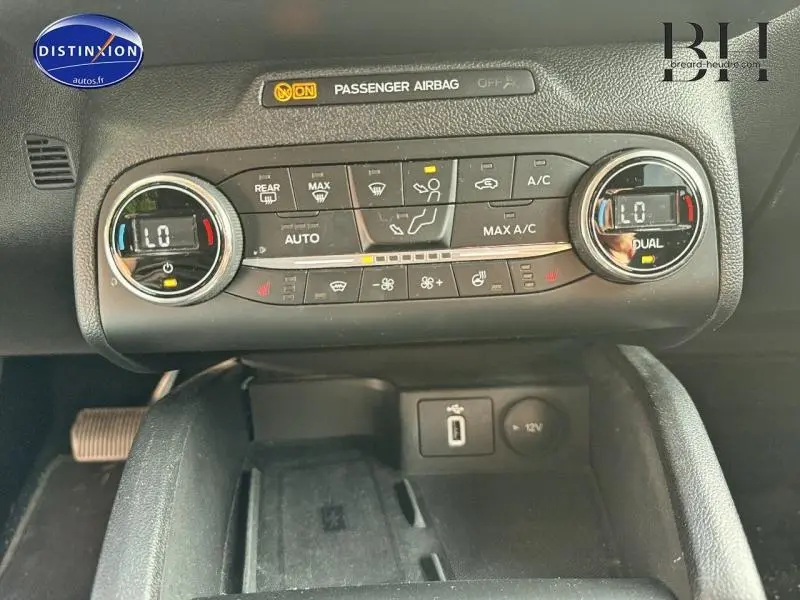 Gros plan sur la console centrale de la Ford Focus 2019, montrant les commandes de climatisation bi-zone et prises USB et 12V.