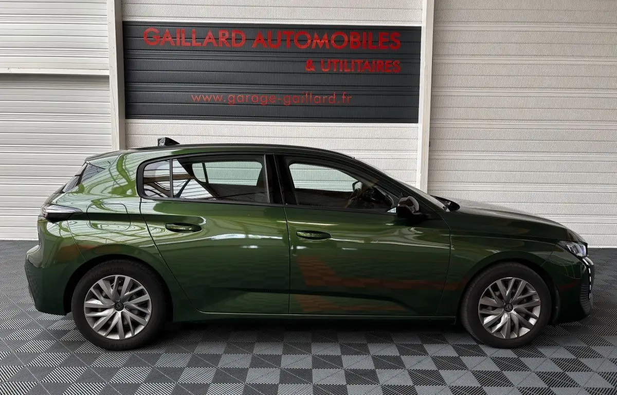 Profil latéral droit d'une Peugeot 308 vert foncé garée devant un mur blanc avec logo rouge Gaillard Automobiles.