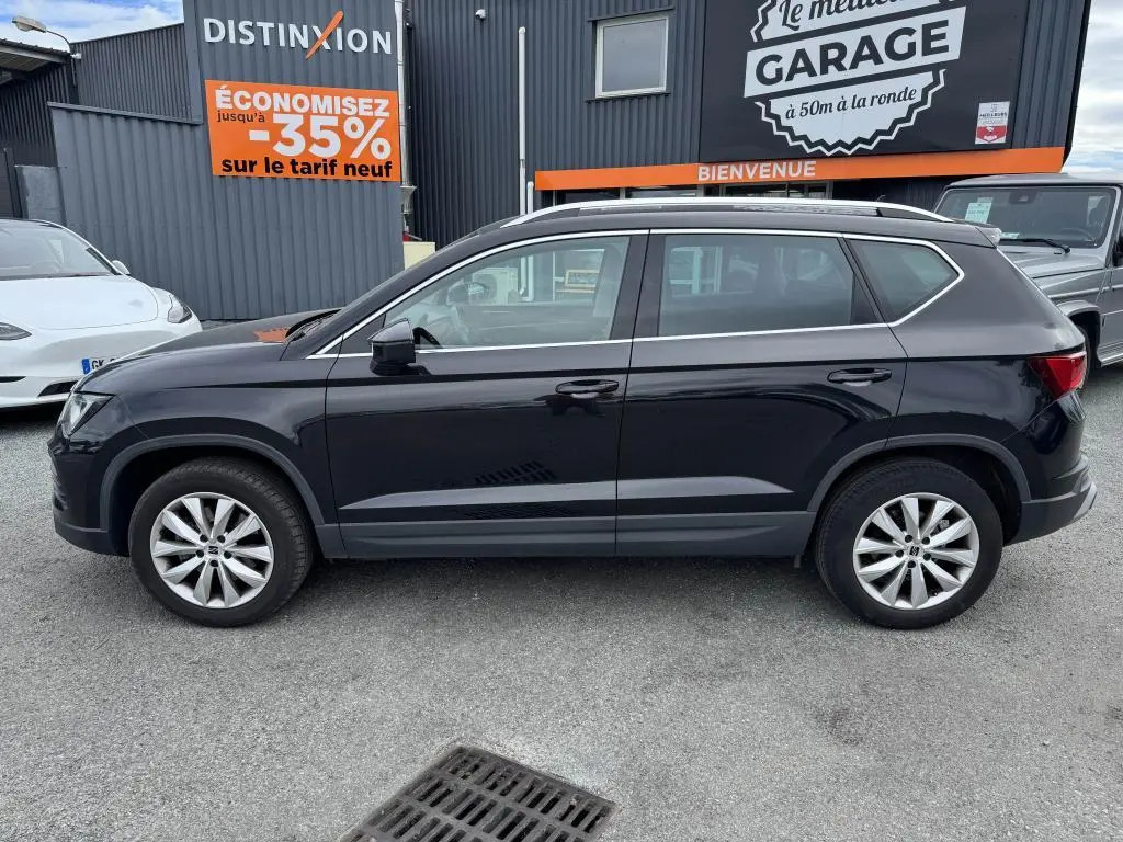 Profil côté gauche d'un SUV SEAT Ateca noir métallisé avec jantes alliage 17'' et barres de toit chromées.