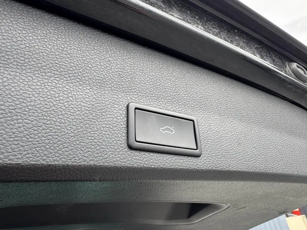 Bouton d'ouverture électrique du coffre sur la garniture intérieure noire du hayon d'un SEAT Ateca noir 2023.