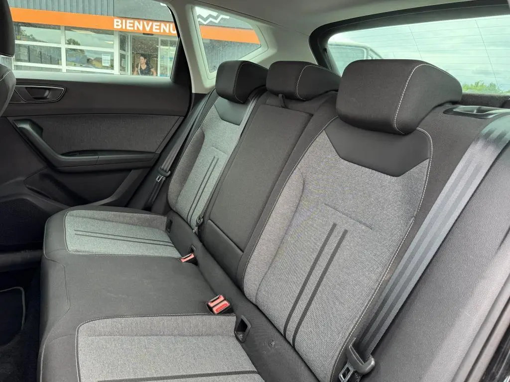 Vue intérieure arrière du SEAT Ateca 2023, sellerie textile gris et noir avec appuie-têtes et ceintures visibles.